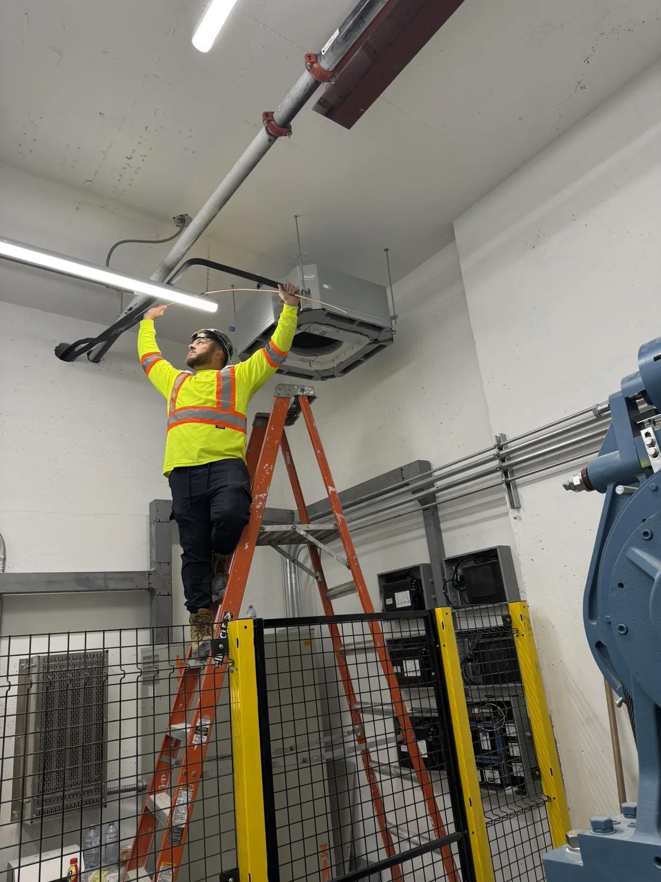 Technician installing a commercial ceiling cassette HVAC unit