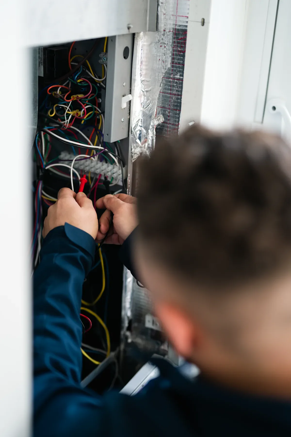 Technician servicing fan-coil electrical controls in a high-rise suite