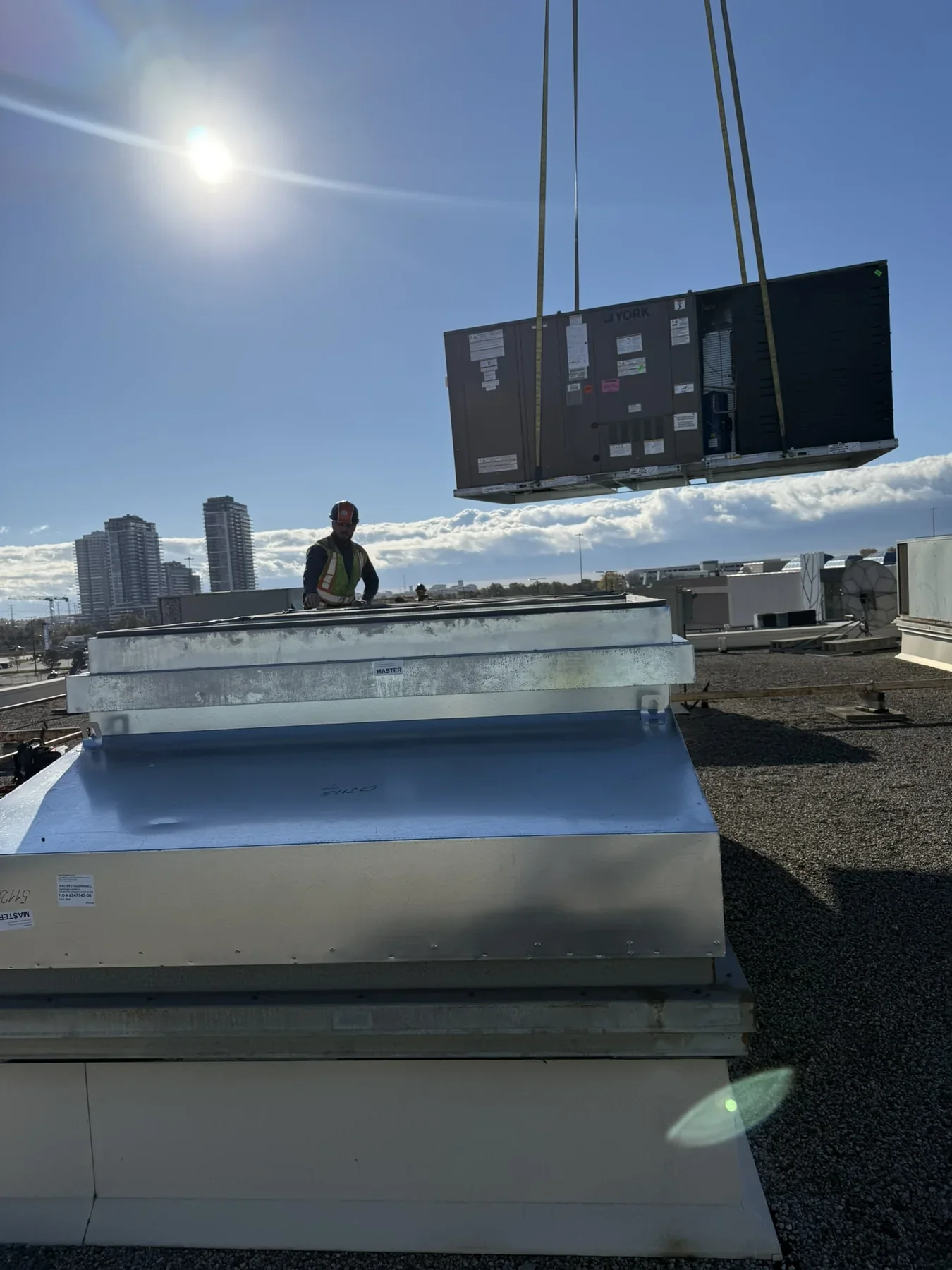 Rooftop HVAC unit being lifted into position by crane